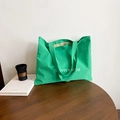 Green nylon tote bag with white lettering on a wooden table, casual aesthetic style - Green