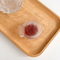 Detail of a frosted translucent red-brown fish-shaped phone grip on a wooden tray - Brown