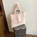 Pink wrinkled fabric tote bag with red text print on a silver metal suitcase - Pink