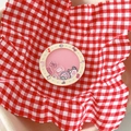 Makroaufnahme eines rosa Kawaii-Shaker-Handyhalters mit niedlichen Charms auf Vichy-Karo - Treibsand Griff-Runde Schleife Cartoon-Gelb