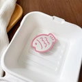 Close-up of pink fish-shaped mirror phone grip placed in a white container - Pink