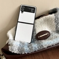Detalle de funda plegable de cuero blanco junto a un bolso de cuadros con textura - Blanco / Samsung ZFlip3