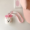 Detail eines weißen Plüschwelpen-Anhängers mit rosa Webband und weichen Stickereien - Errötender Hund