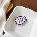 Close-up of cute fish-shaped phone grip mirror with white enamel and purple trim - Deep purple