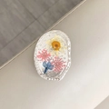 Makrodetail der ovalen Halterung mit echten Trockenblumen und Silberfolie in Harz - Oval Echtblume-Silberfolie Weiße Gänseblümchen