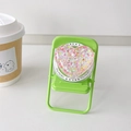 Macro detail of heart-shaped glitter Magsafe phone grip on a mini green chair prop - Heart Shapes Sequin