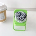 Magnetic heart phone grip with black and white ink splatter texture on a mini green chair - Black and White Sequins