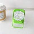 Close-up of heart-shaped MagSafe phone grip with colorful sequins on a mini green chair - Shell Pattern