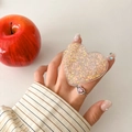 Dettaglio del supporto per telefono a cuore con paillettes colorate tenuto in mano - Oro