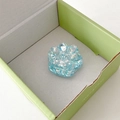 Close-up of translucent light blue cat claw phone grip with iridescent sequins in a box - Blue