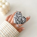 Detail of heart-shaped grip tok with black and white glitter flakes on a hand - Transparent Stand - 3D Heart - Black & White Sequins