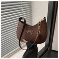 Detalle de bolso hobo marrón con lazo dorado y una elegante correa de cadena metálica fina - café