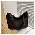 Dettaglio della borsa hobo in nylon nero con tracolla larga su libri bianchi puliti - Nero