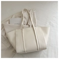 Detail of minimalist cream leather tote bag with FASHION lettering on textured surface - White