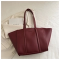 Macro shot of dark red bucket tote bag with embossed fashion text and chic accessories - Red
