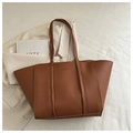 Macro detail of brown leather tote bag with FASHION embossed text and slim straps - Brown