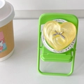 Macro view of bright yellow heart phone grip with silver bow on a mini green chair - Pearl Yellow