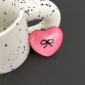 Detail of pink crystal heart phone grip featuring a black bow design on a resin surface - Rose Red