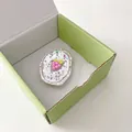 Détail d'une breloque raisin rose pailletée dans un support ovale en métal - Support Transparent - Raisin Ovale Glace Pilée