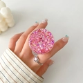 Close-up of a pink glitter phone grip and heart ring on a manicured hand - Pink Hexagonal Glitter Style (9)