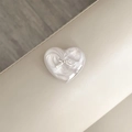 Close-up of a heart-shaped phone grip with pearl texture and a silver bow accent - Silver Grey