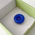 Close-up of a large dark blue four-hole button phone socket inside a green gift box - Royal Blue