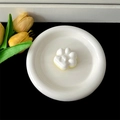 Close-up view of a cute white cat paw shaped phone grip stand placed in a minimalist ceramic dish - Transparent Stand / White