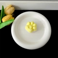 Close-up view of a cute yellow cat paw shaped phone grip with heart detail on a plate - Transparent Stand / Yellow