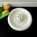 Top-down view of a mint green cat paw phone grip on a white decorative plate. - Magnetic Stand / Light Green