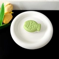 Close-up of a green fish-shaped phone grip on a white plate with yellow tulips - Transparent Stand - Two-tone Fish / Dark Green