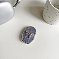 Macro shot of glitter blue resin phone grip featuring a silver 3D bow and wave-textured edge - Purple