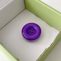 Macro shot of dark purple button phone grip with a glossy mirror finish in a gift box - Dark Purple