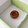 Close-up of a dark brown glossy button phone socket with a four-hole sewing design - Brown