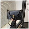 Close-up of black leather underarm bag featuring a vintage gold oval metal clasp detail - Black