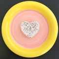 Detail view of heart-shaped glitter phone grip with silver sequins in a ceramic dish - Silver