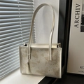 Cremeweiße Shopper-Tasche mit goldenem Schmetterlingsdruck und Quasten im Sonnenlicht - Weiß