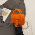 Vibrant orange mini leather handbag with silver chain strap and top handle on grey blazer - Orange