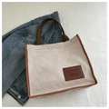 Detailed shot of a corduroy tote bag featuring brown leather trim and a fashion logo label - Off White