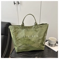 Detail of green waterproof DuPont paper tote bag with white TOTE BAG text on a desk - Green