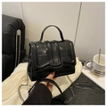 Detalle de bolso negro con textura de cocodrilo, cadena metálica y asa fija - Negro