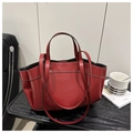 Detailed view of red leather tote bag showing double handles and interior space on desk - Red
