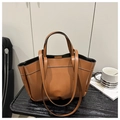 Detail of vintage caramel leather tote bag with sturdy handles on a textured table - Brown