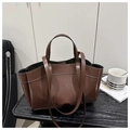 Close-up of a brown leather tote bag with white stitching detail on a modern desk - Coffee