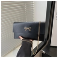 Λεπτομέρεια μαύρου φακέλου clutch με χρυσό φιόγκο και λεπτή μεταλλική αλυσίδα ώμου - Μαύρο