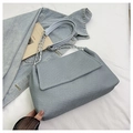 Detalle de bolso tote de mezclilla azul claro con correa de cadena sobre fondo blanco - Azul