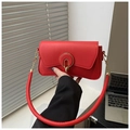 Detalle del bolso rojo de cuero con hebilla dorada redonda y correa tubular moderna - Rojo