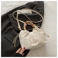 Detail des Perlengriffs an creme-farbener Kordeltasche über grauem Anzug für Stil - Weiß
