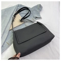 Detalle de bolso tote negro tejido con correa de cadena y textura acolchada minimalista - Negro