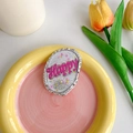 Detail eines glitzernden pinkfarbenen 'Happy' Handyhalters mit silbernem Hammerschlag - Oval Happy