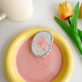 Nahaufnahme der Glitzer-Handyhalterung mit rosa Schleife auf schickem Keramikteller - Oval Transparent Rosa Schleife